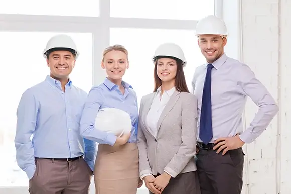 A group of people wearing hard hats and smiling.