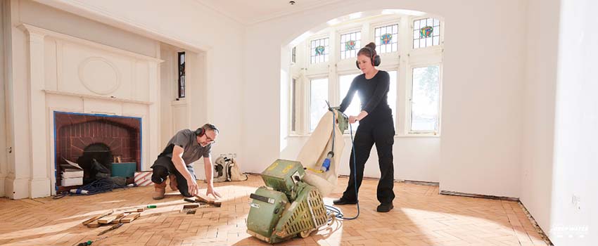 A woman and man are cleaning the floor.