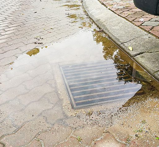 A puddle of water on the ground next to a street.