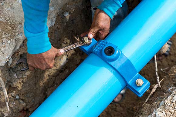 A person is working on the pipe of a blue water supply.