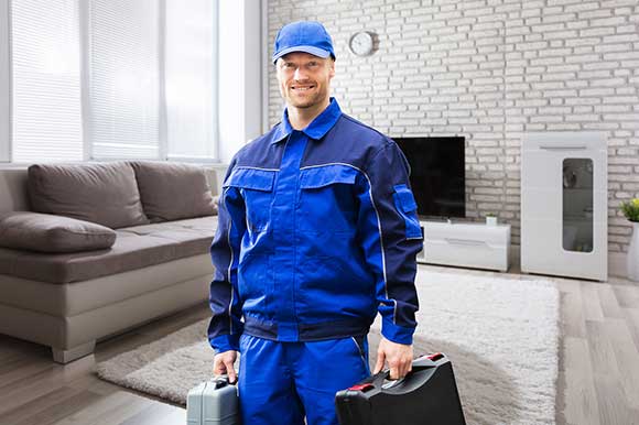 A man in blue and white holding two black suitcases.