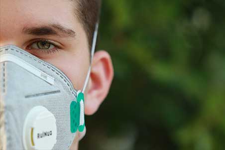 A man wearing a mask with trees in the background.