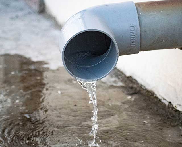 A pipe that is leaking water from the side of a wall.