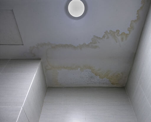 A bathroom with a ceiling that has water stains on it.