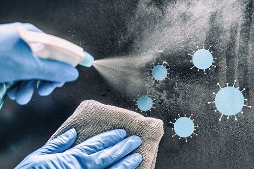 blue-gloved hands spraying and wiping on a surface to prevent contamination