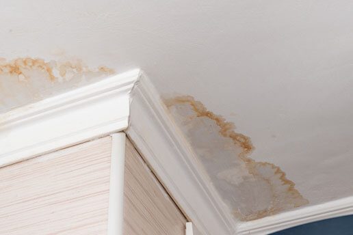 A ceiling with water stains on it and the roof of the room.