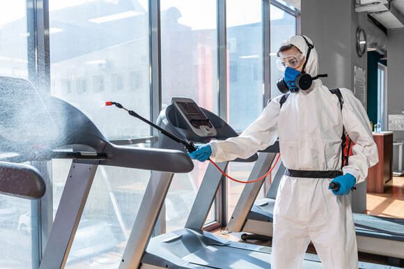 A man in white suit and mask on treadmill.