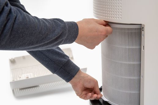 A person is adjusting the air filter on an air conditioner.