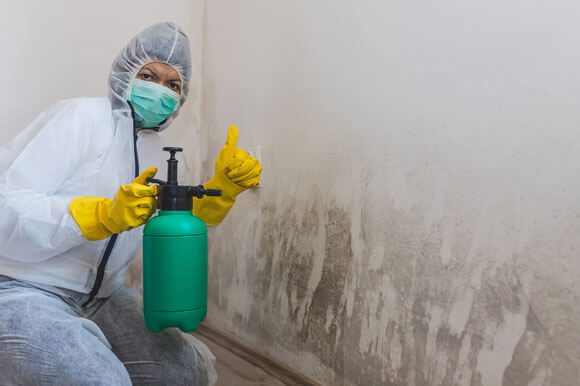 A person in yellow gloves holding a green bottle.