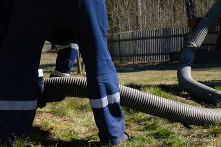 A person in blue pants and white shirt holding hose.