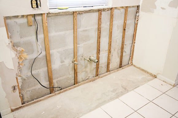 A bathroom wall being built with wood and tile.