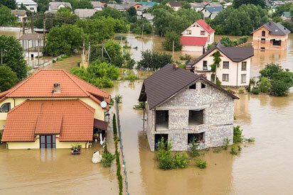 A flooded area with houses and trees in the background.