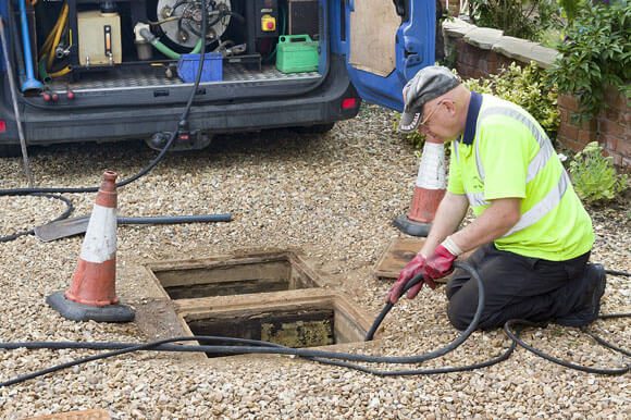 A man in an orange vest is working on a hole.