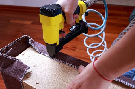 A person using a nail gun to attach the coil of cardboard.