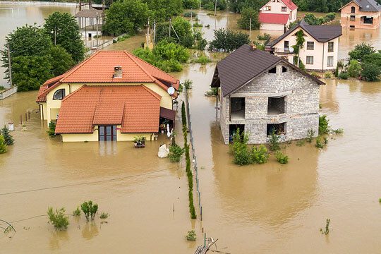 A flooded area with houses and trees in the background.