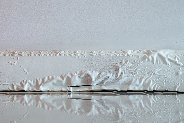 A white skirting board damaged by flooding water