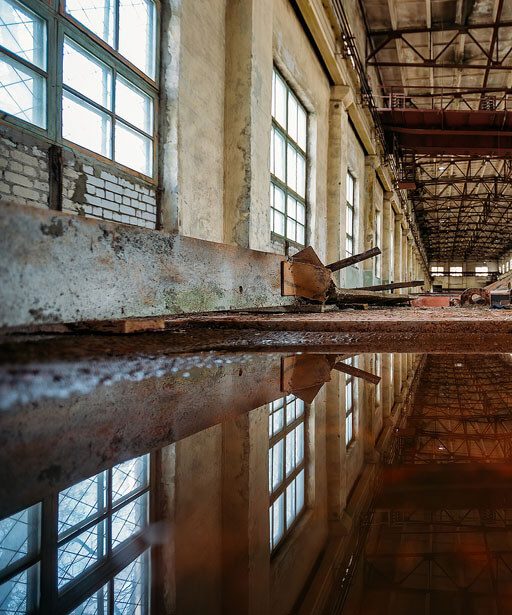 A large warehouse with windows and a reflection of the floor.