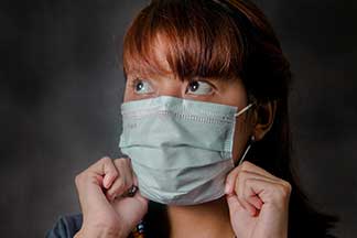 A woman putting on her surgical mask
