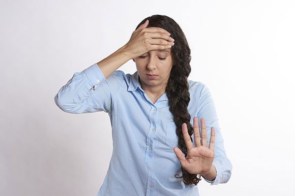 A woman holding her hand up to the side of her head.