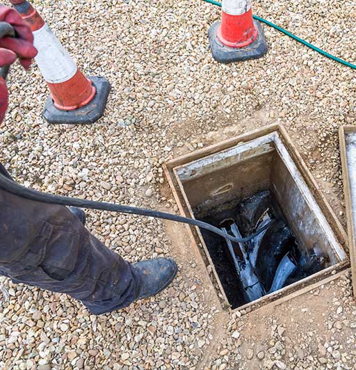 A man is standing in the dirt near some pipes.