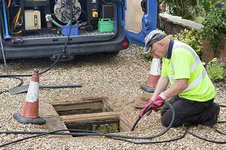 A man in yellow shirt using an electric drill.