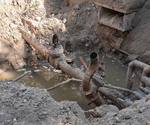 A pipe that is in the dirt near some rocks.