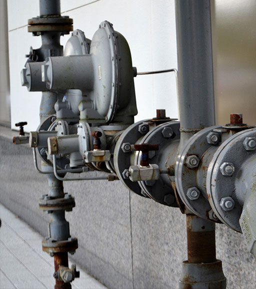 A close up of pipes and valves on the side of a building.