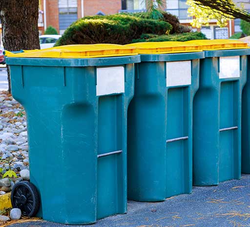 A blue trash can with some bushes on top of it