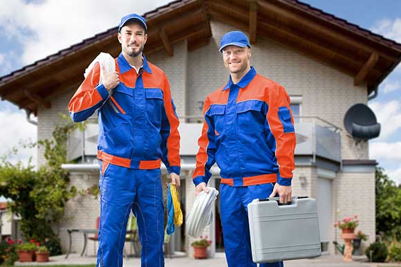 Two men in blue and orange work clothes holding a tool box.